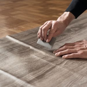 Closeup of carpenters hands removing air from self-adhesive film